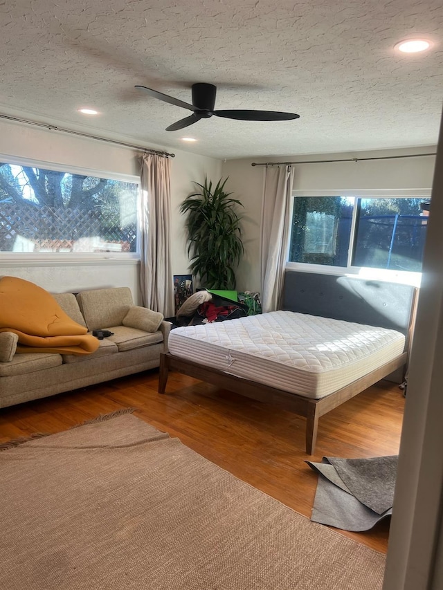 bedroom with ceiling fan, hardwood / wood-style floors, and a textured ceiling