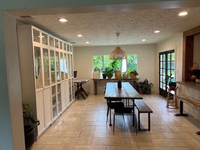 dining space with french doors and a textured ceiling