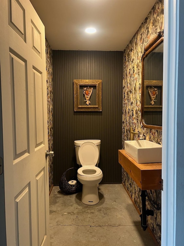 bathroom featuring sink, concrete flooring, and toilet