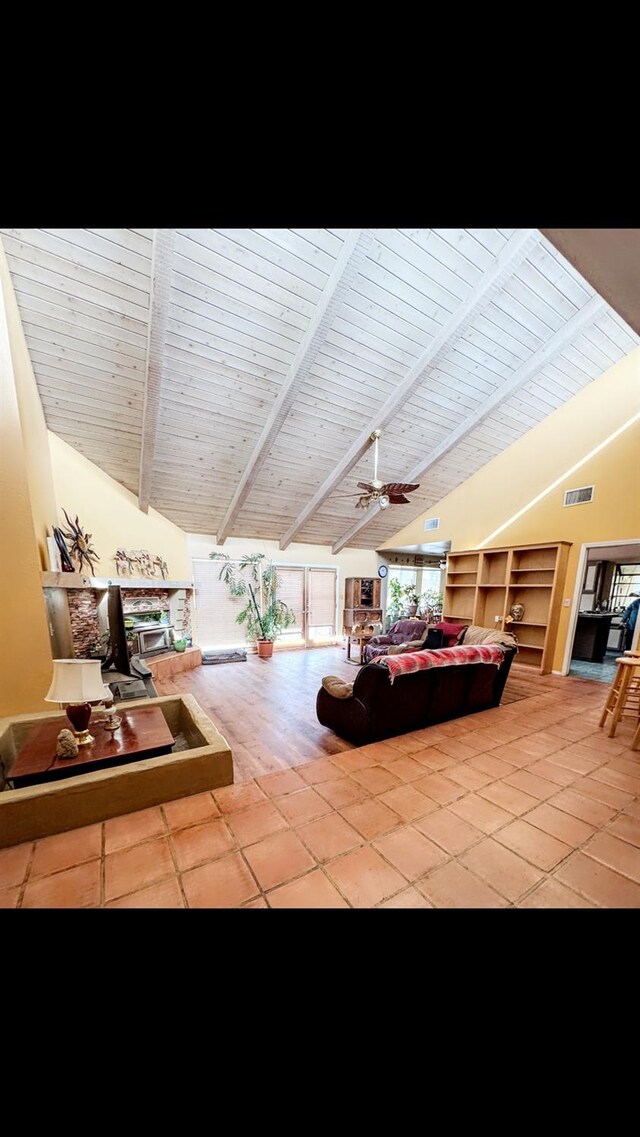 tiled living room featuring lofted ceiling with beams, wooden ceiling, and ceiling fan