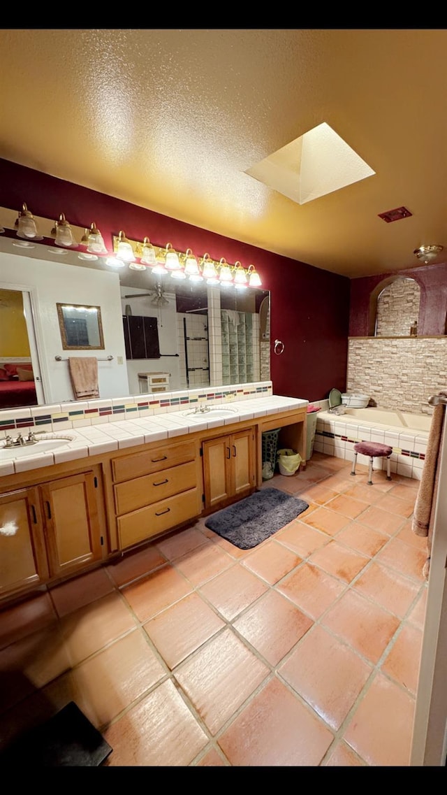 bathroom with a skylight, a tub, vanity, tile patterned floors, and a textured ceiling