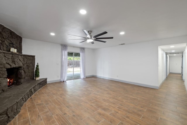 living room with ceiling fan, light wood-type flooring, and a fireplace