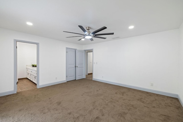 unfurnished bedroom with ceiling fan, light colored carpet, and ensuite bathroom