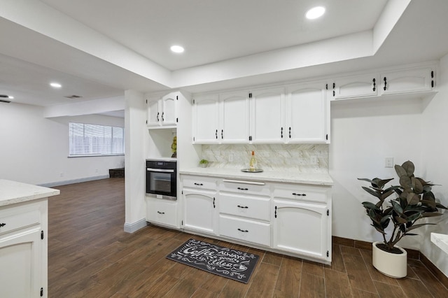 kitchen with white cabinetry, oven, dark wood-type flooring, and tasteful backsplash