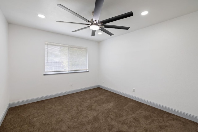 spare room featuring dark carpet and ceiling fan