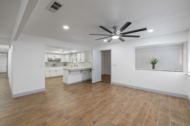 unfurnished living room featuring hardwood / wood-style flooring, ceiling fan, and sink