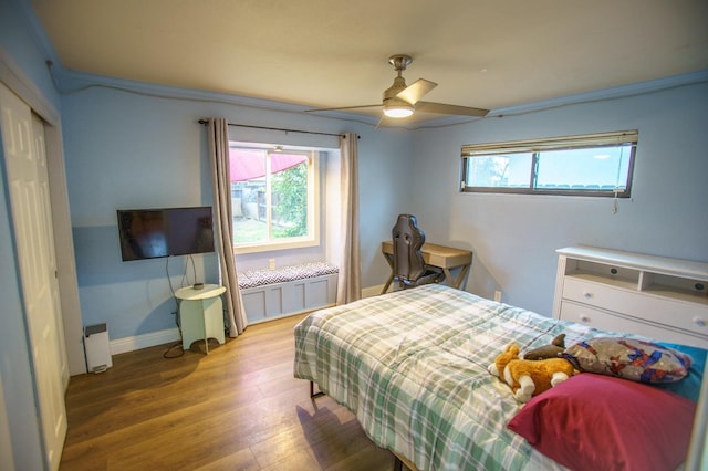 bedroom featuring ceiling fan, wood-type flooring, a closet, and multiple windows