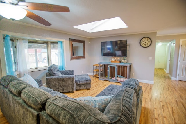 living room with ceiling fan, ornamental molding, a skylight, and hardwood / wood-style floors