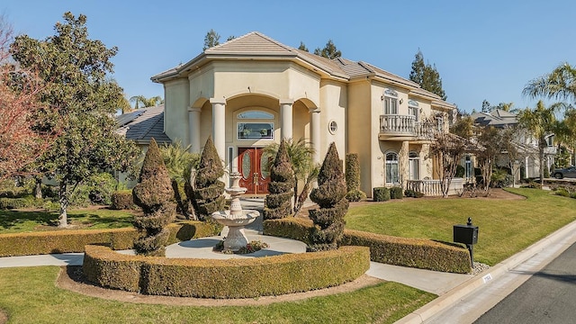 mediterranean / spanish-style house featuring a front lawn and a balcony