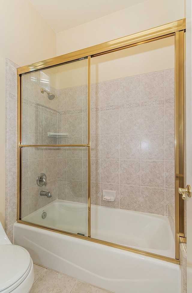 bathroom with combined bath / shower with glass door, tile patterned floors, and toilet