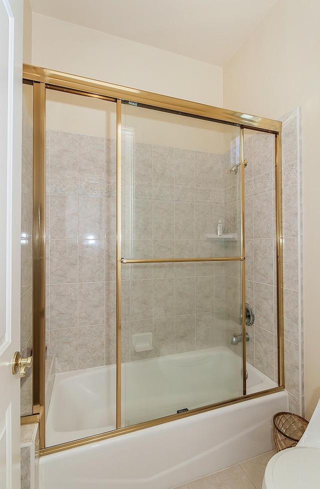 bathroom featuring enclosed tub / shower combo, tile patterned floors, and toilet