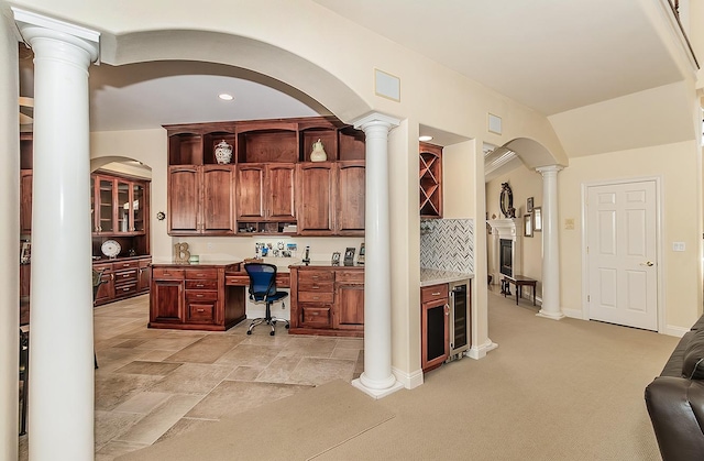 carpeted home office with wine cooler, built in desk, and ornate columns