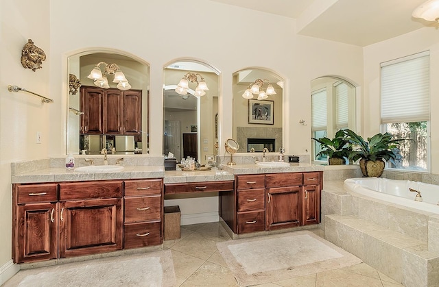 bathroom with tiled tub, vanity, tile patterned flooring, and a tile fireplace