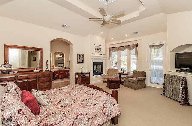 bedroom with connected bathroom, access to exterior, ceiling fan, a tray ceiling, and light carpet