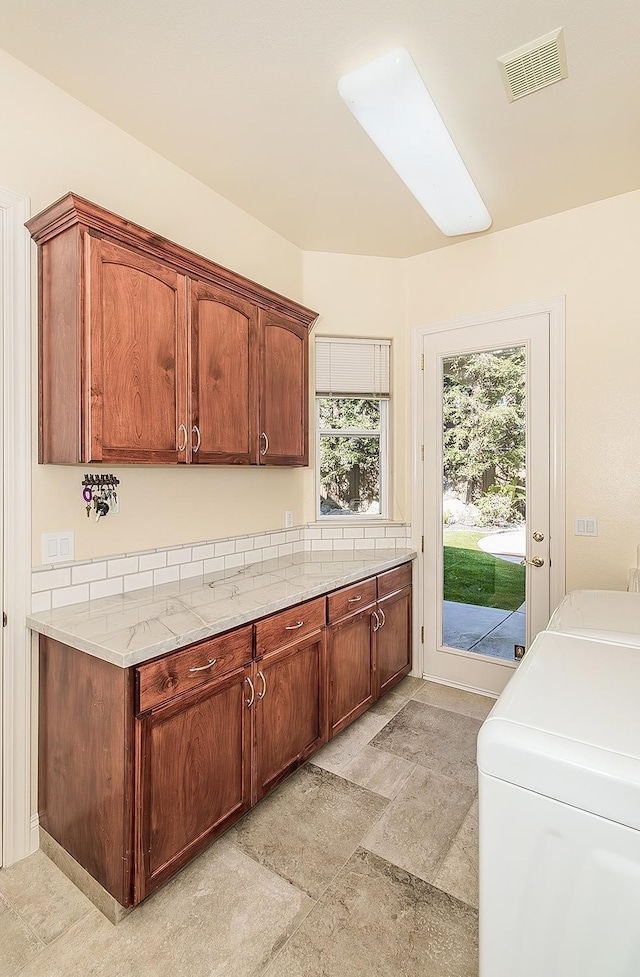 kitchen with light stone counters and washing machine and clothes dryer