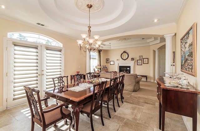 dining room with a raised ceiling, crown molding, french doors, and ornate columns