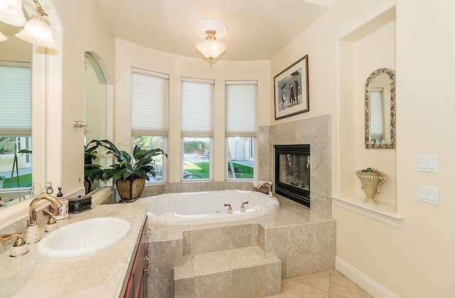 bathroom with vanity, tile patterned flooring, a tile fireplace, and tiled bath