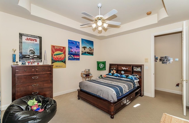 carpeted bedroom featuring ceiling fan and a tray ceiling