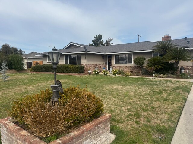 ranch-style home featuring a front lawn and brick siding