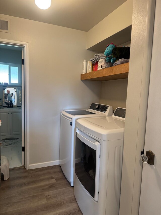 washroom featuring laundry area, separate washer and dryer, dark wood-type flooring, visible vents, and baseboards