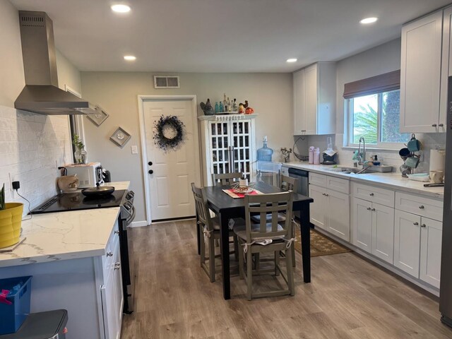 kitchen with wall chimney range hood, black / electric stove, and white cabinets