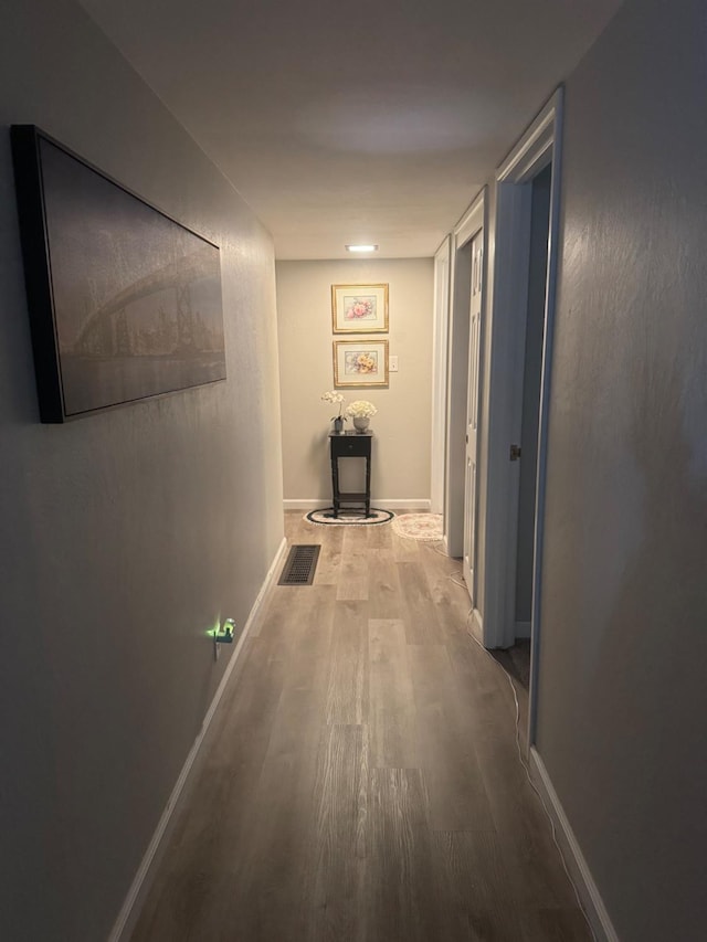 corridor with visible vents, baseboards, and wood finished floors