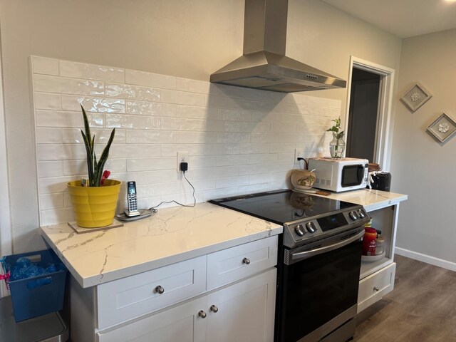 kitchen featuring white microwave, white cabinets, ventilation hood, light stone countertops, and stainless steel range with electric stovetop