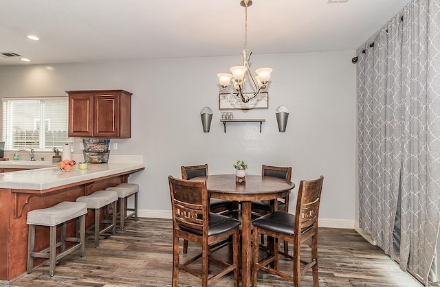 dining space featuring sink, a notable chandelier, and dark hardwood / wood-style flooring