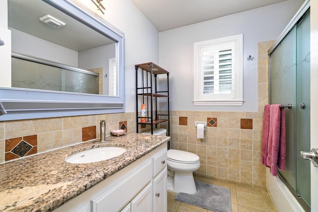 full bathroom with toilet, shower / bath combination with glass door, tile walls, vanity, and tile patterned flooring