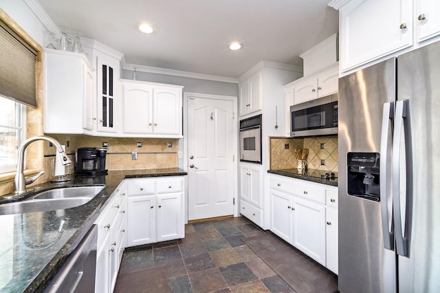 kitchen featuring sink, appliances with stainless steel finishes, dark stone counters, decorative backsplash, and white cabinets