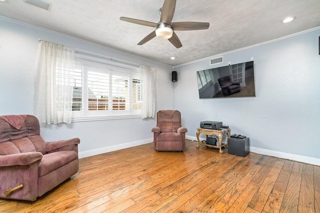 living area with ceiling fan, ornamental molding, light hardwood / wood-style flooring, and a textured ceiling