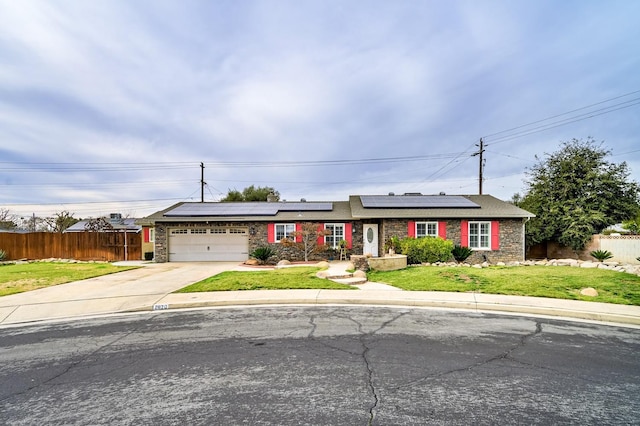 single story home featuring a garage, a front yard, and solar panels