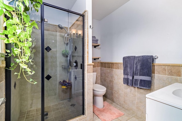 bathroom with a shower with door, vanity, tile walls, and toilet