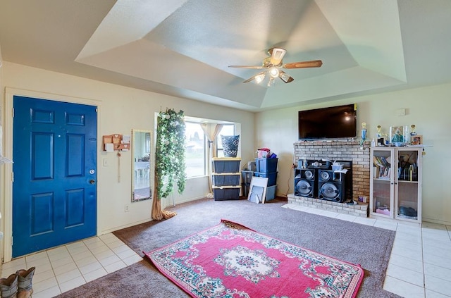 living room featuring light tile patterned floors, ceiling fan, and a tray ceiling