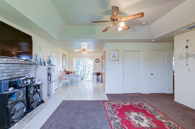 entryway featuring light carpet, ceiling fan, and a tray ceiling