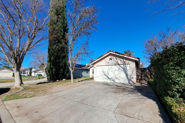 view of home's exterior with a garage, driveway, a tiled roof, and stucco siding