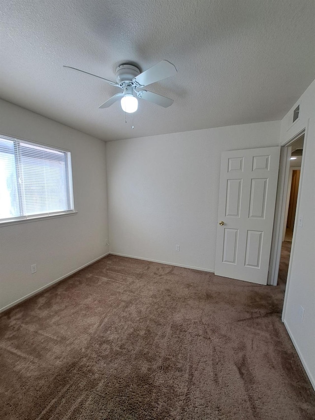 carpeted spare room with visible vents, ceiling fan, a textured ceiling, and baseboards