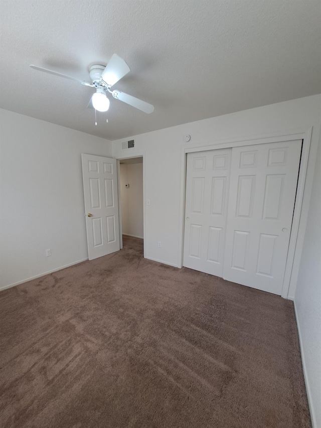 unfurnished bedroom with visible vents, a ceiling fan, a textured ceiling, carpet flooring, and a closet