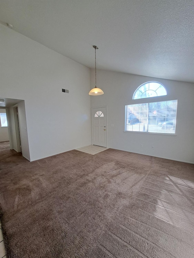 interior space with high vaulted ceiling, visible vents, and a textured ceiling