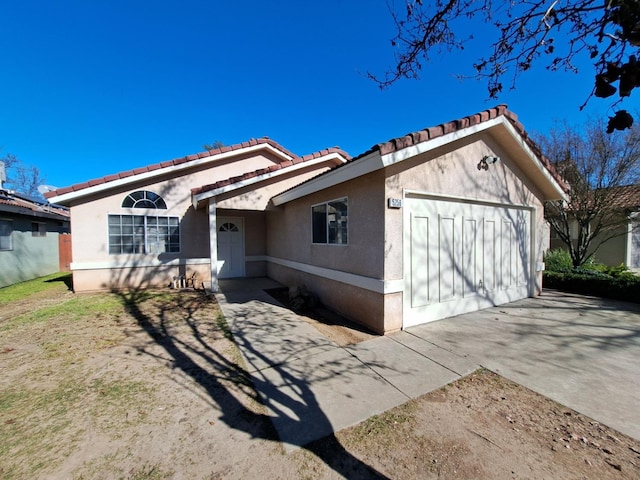 view of front of house with a garage, concrete driveway, a tiled roof, and stucco siding