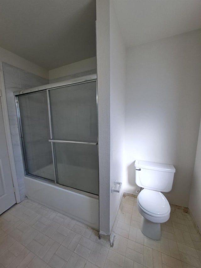 bathroom featuring combined bath / shower with glass door and toilet