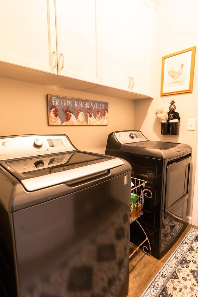 washroom featuring cabinets, washing machine and dryer, and light wood-type flooring