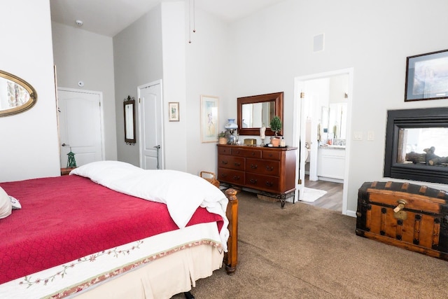 carpeted bedroom with a multi sided fireplace, ensuite bathroom, and high vaulted ceiling