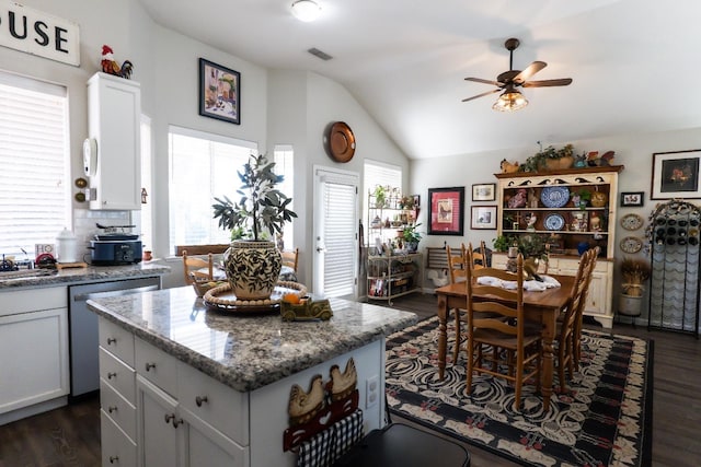 kitchen with a center island, dark hardwood / wood-style flooring, light stone countertops, and dishwasher