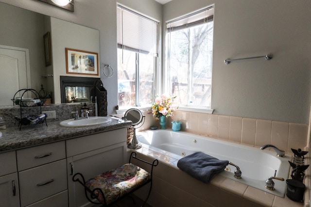 bathroom featuring vanity, plenty of natural light, tiled bath, and a multi sided fireplace