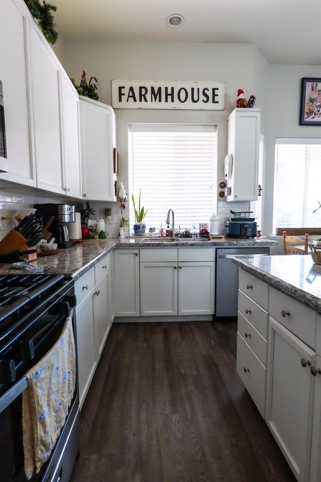 kitchen featuring sink, white cabinetry, range, stainless steel dishwasher, and light stone countertops