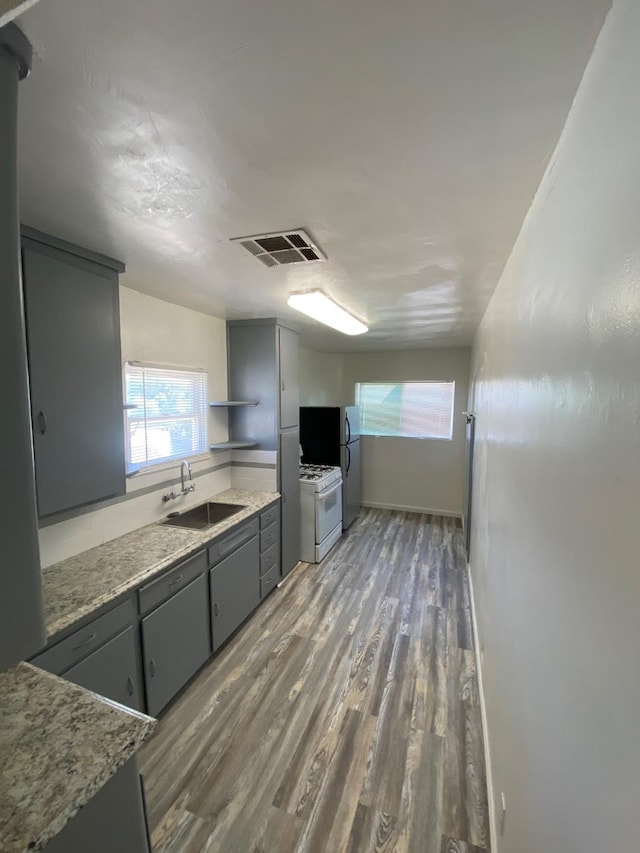 3185 W Mckinley, Fresno, CA 93722 - kitchen featuring white gas range oven, gray cabinets, visible vents, a sink, and wood finished floors