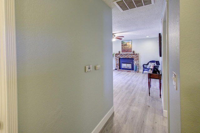 hallway featuring a textured ceiling and light wood-type flooring