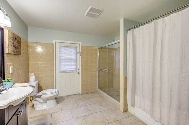 bathroom featuring walk in shower, toilet, tile walls, vanity, and tile patterned flooring