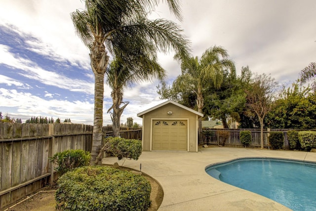 view of swimming pool featuring a garage and an outbuilding